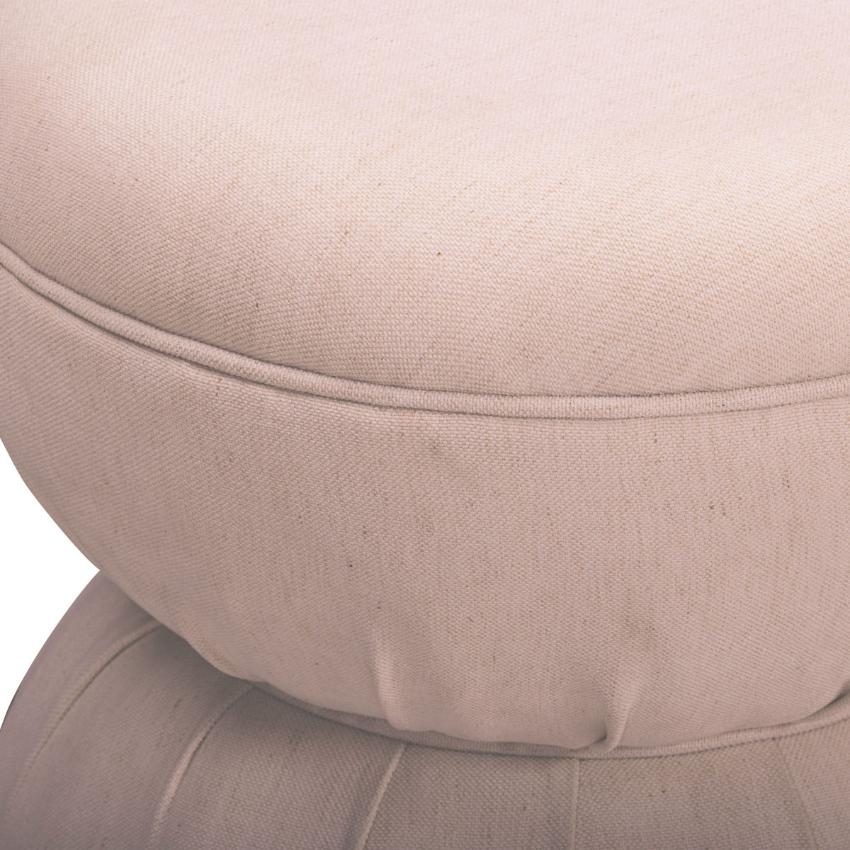 Close-up of light pink-beige ruched upholstered ottoman with stitched seam