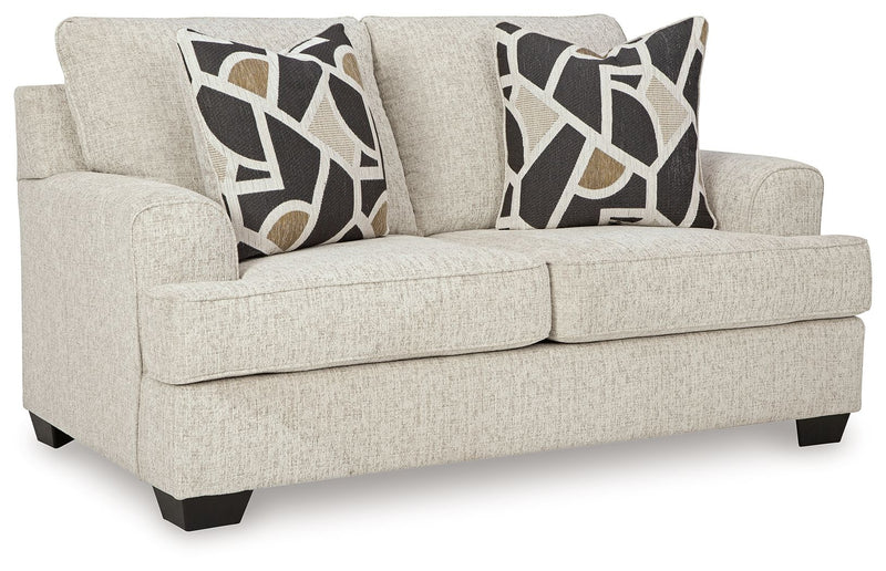 Beige loveseat with geometric black-and-cream pillows, cushioned arms and skirted base