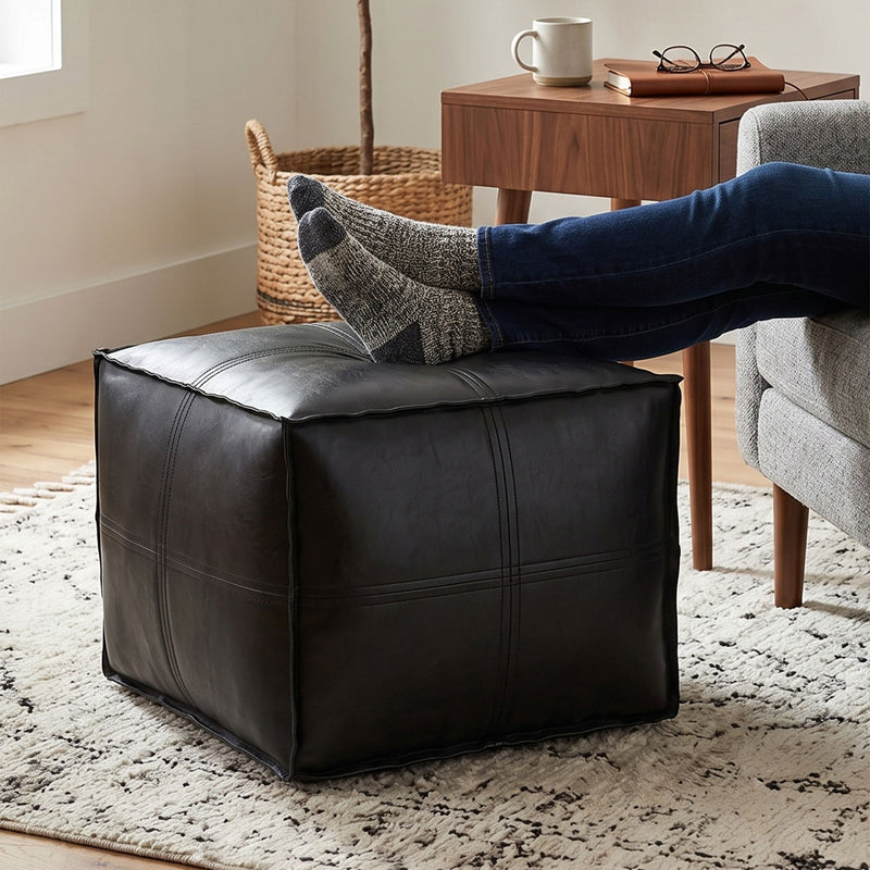 Black square pouf with stitched panels and tufted top cushion.
