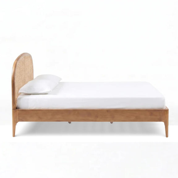 Light brown rattan bed with woven backrest panel and white fitted mattress