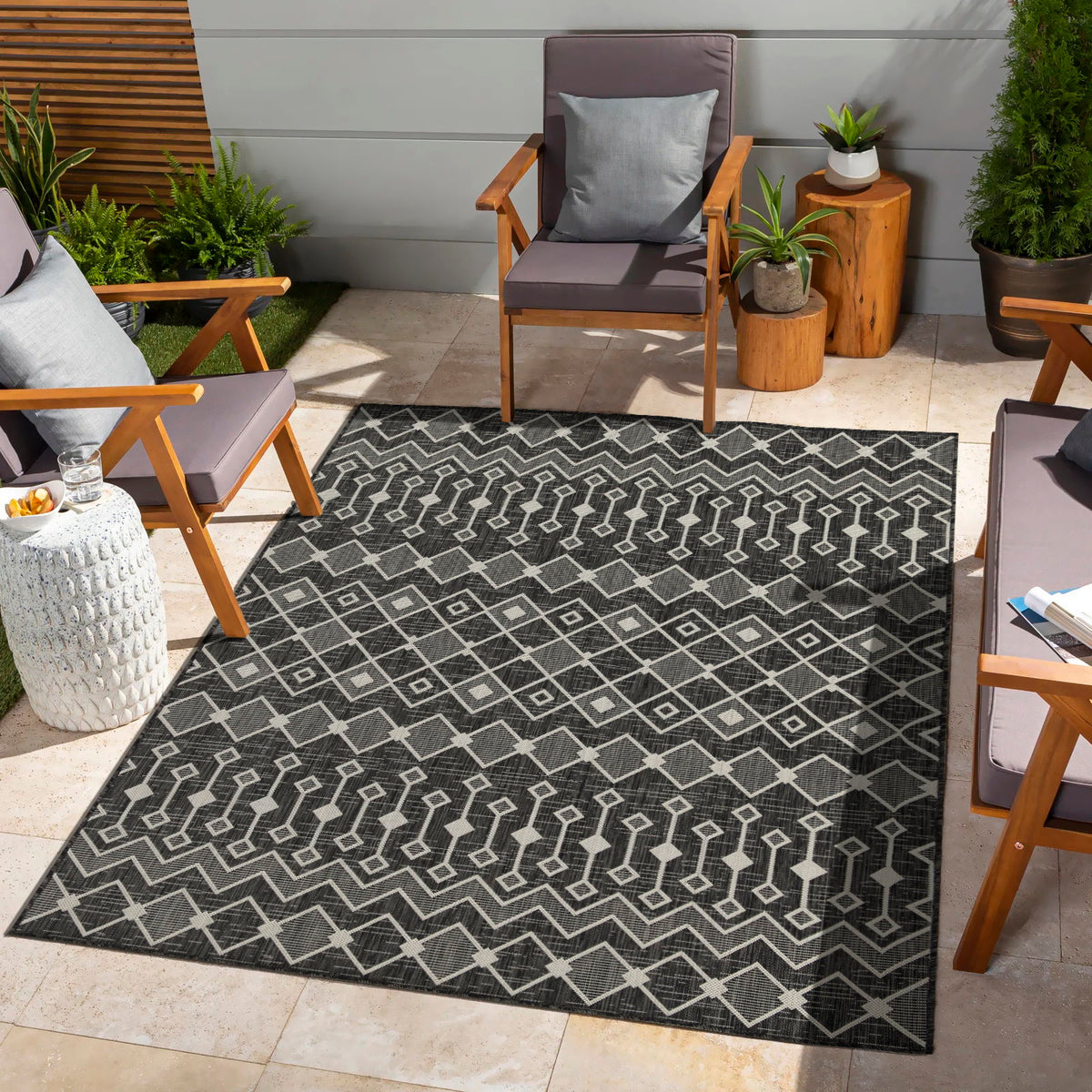 Indoor/outdoor polypropylene area rug, dark charcoal with white geometric line and diamond pattern.