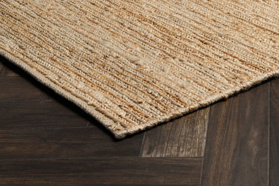 Natural tan jute rug corner detail on hardwood, flatwoven textured weave.