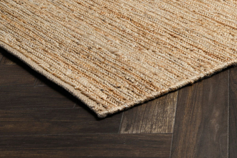 Natural tan jute rug corner detail on hardwood, flatwoven textured weave.