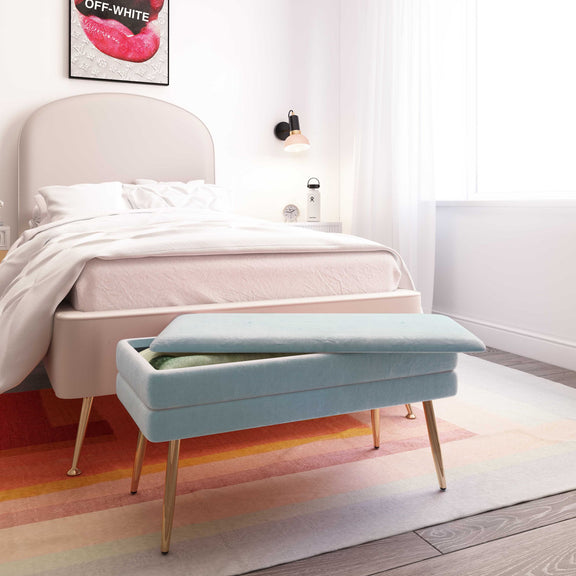 Light blue velvet storage bench in a bedroom setting with tapered gold legs