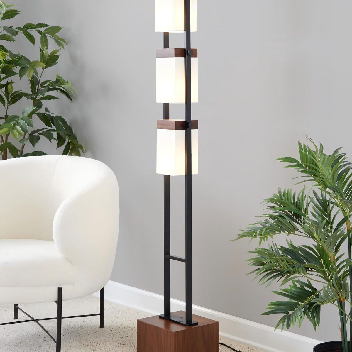 Black standing lamp with three white cube shades on a vertical metal frame