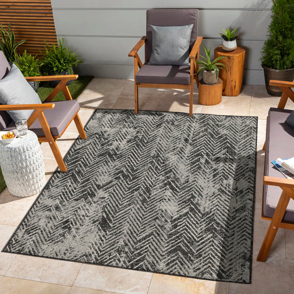 Indoor/outdoor area rug with dark gray and cream chevron pattern and flat surface.
