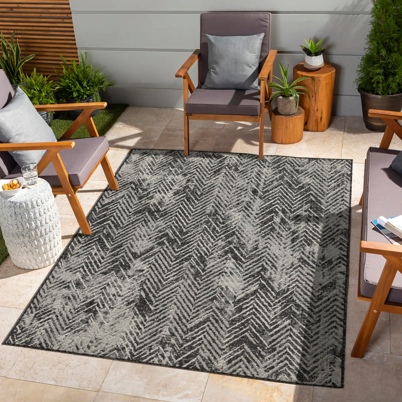 Indoor/outdoor area rug with dark gray and cream chevron pattern and flat surface.