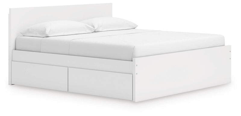 White platform bed with panel headboard and drawer storage, neatly styled bedding