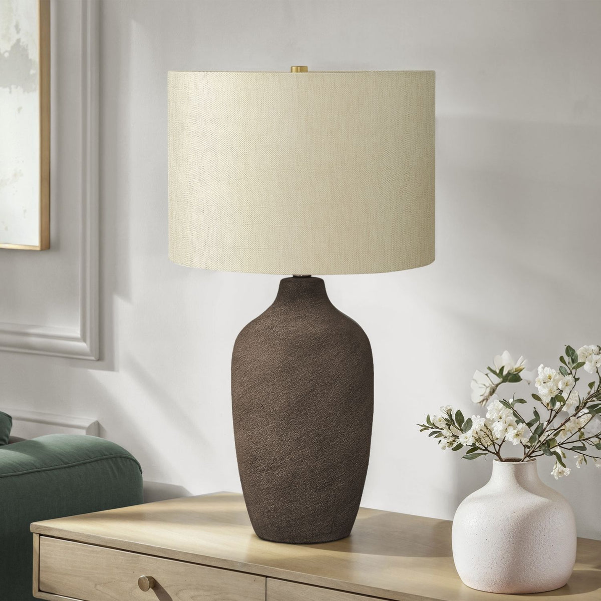 Dark gray ceramic table lamp with textured body and off-white drum shade