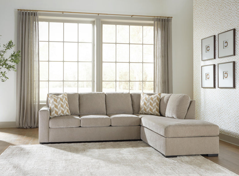 Beige corner chaise sectional sofa with multiple back cushions and patterned accent pillows.