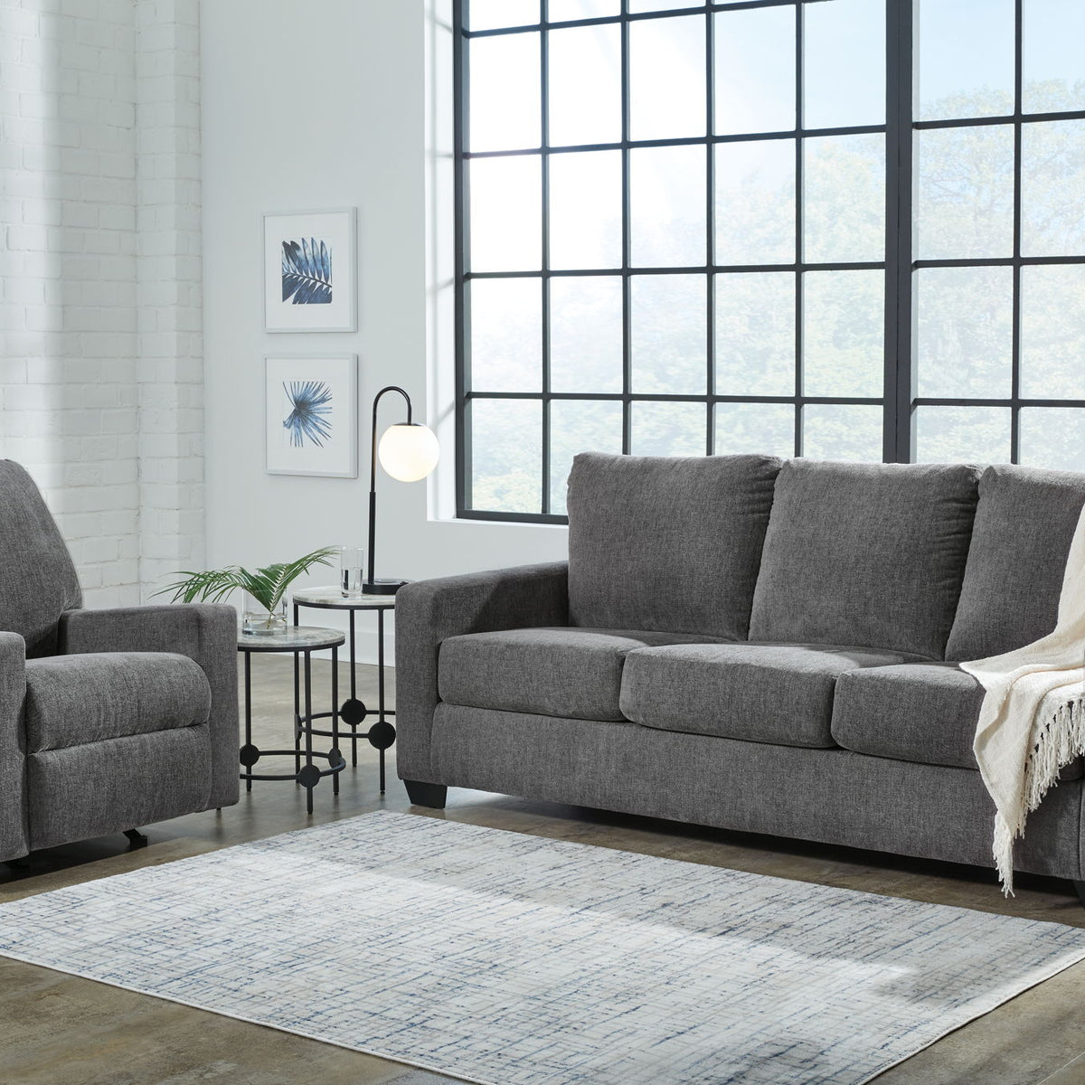 Dark gray sofa set with an extra armchair, square arms, and draped throw blanket