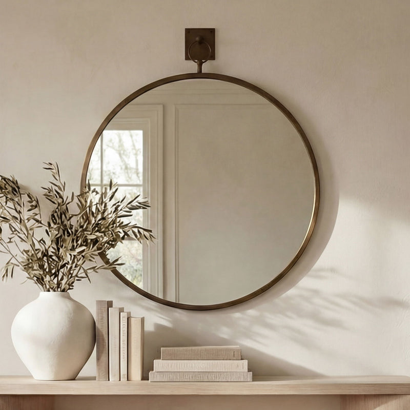 Wall-mounted round mirror with aged brass frame and back bracket