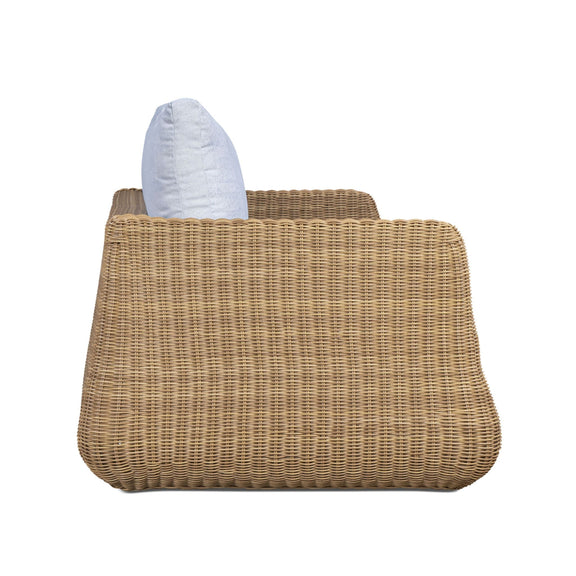 Outdoor sofa side view with white back pillow on brown woven wicker