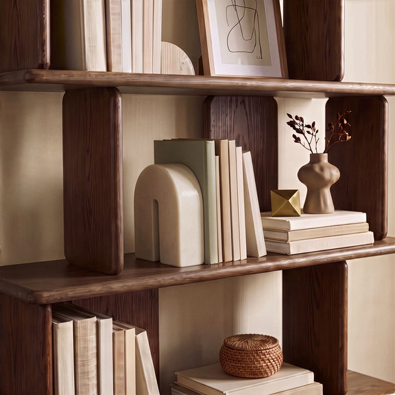 Cream marble bookend with arched cutout, placed on wooden shelf