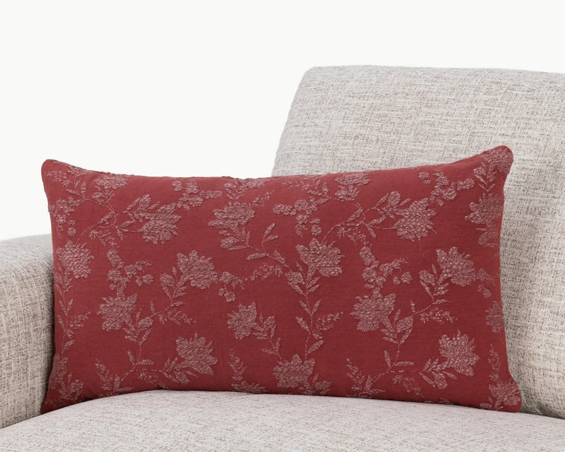 Burgundy red floral throw pillow with repeating vine and leaf pattern on textured fabric.