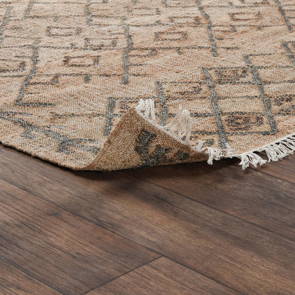 Rug corner detail: beige-and-sage geometric pattern with tassel fringe.