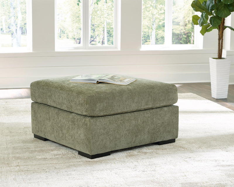 Oversized accent ottoman in green fabric with black legs and magazine on top