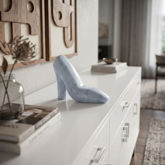 Light blue marble high-heel shoe sculpture displayed on a white console