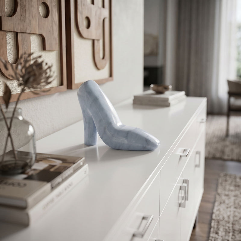 Light blue marble high-heel shoe sculpture displayed on a white console