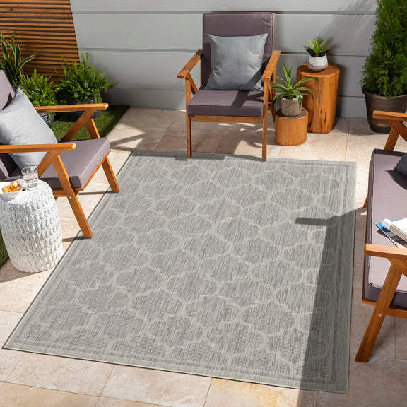 Gray polypropylene area rug with repeating quatrefoil pattern and bordered edges