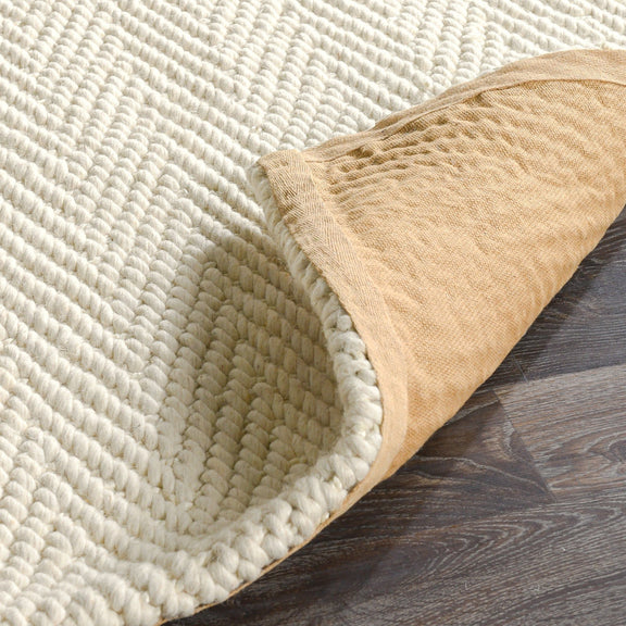 Chenille rug corner detail in cream with beige border and looped herringbone texture