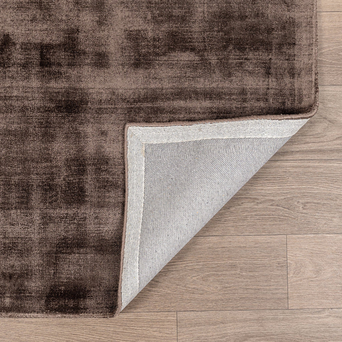 Distressed area rug in brown/taupe with faded pattern and light border edge.