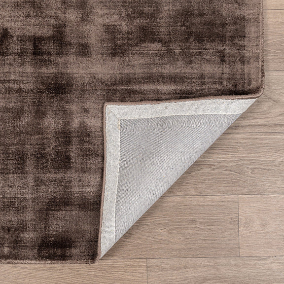 Distressed area rug in brown/taupe with faded pattern and light border edge.