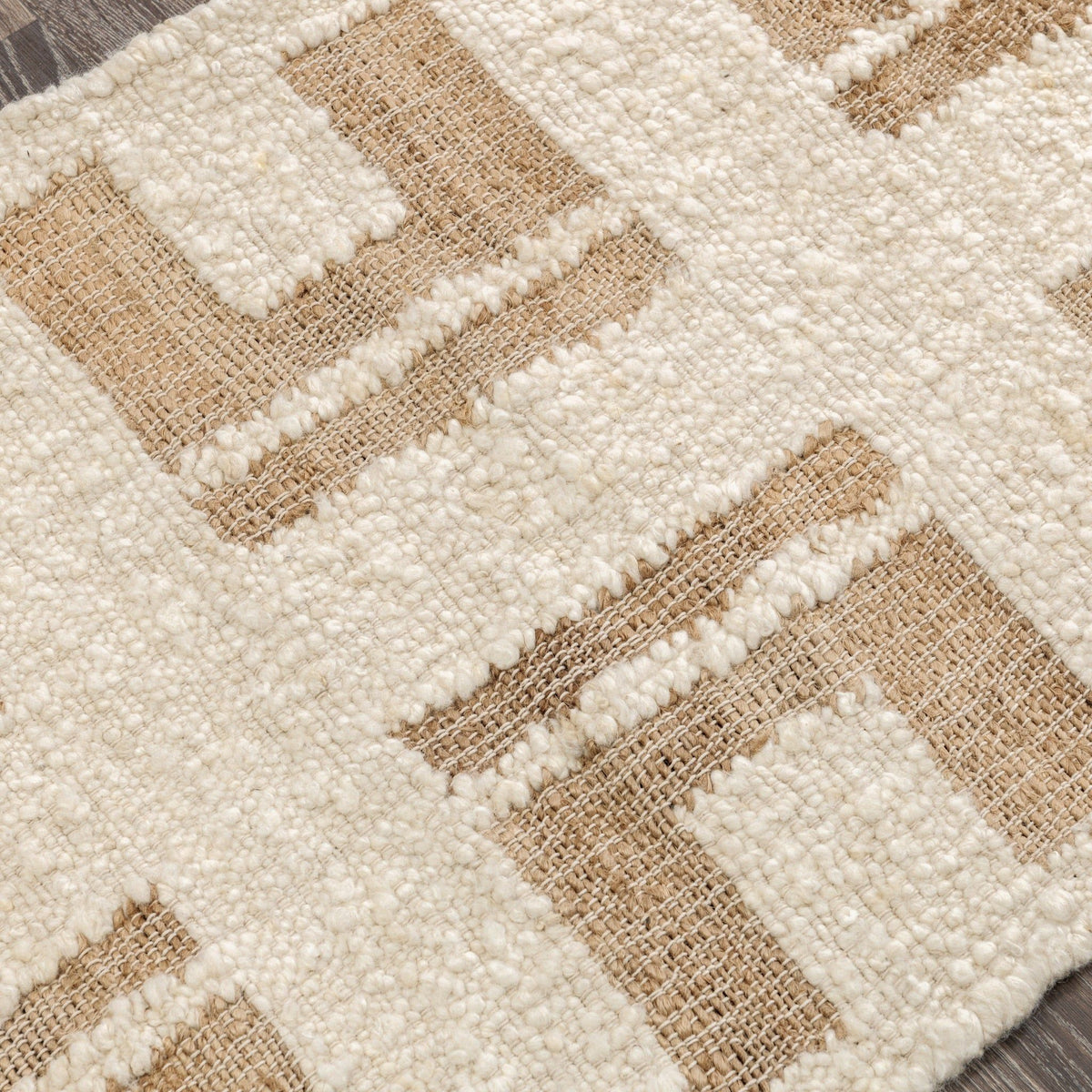 Close-up of cream and tan geometric area rug texture with raised stitched pattern