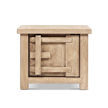 Light brown wooden side table with square carved panel on front and open lower shelf