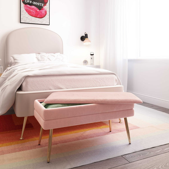 Pink velvet storage bench in a bedroom setting with tapered gold legs