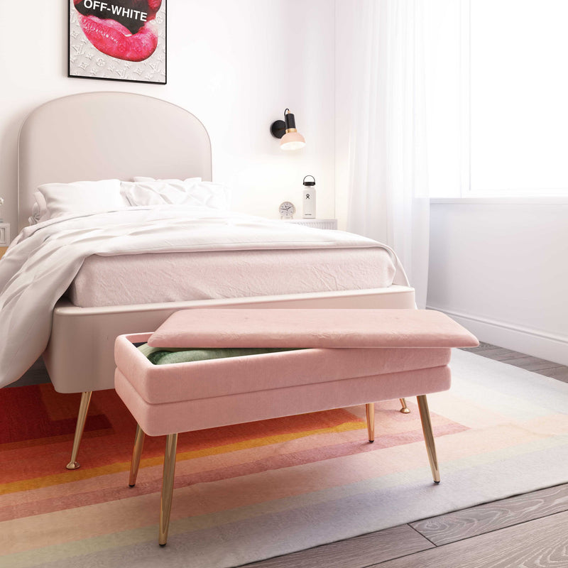 Pink velvet storage bench in a bedroom setting with tapered gold legs