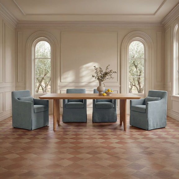 Natural wood dining table with four upholstered chairs in a light room setting