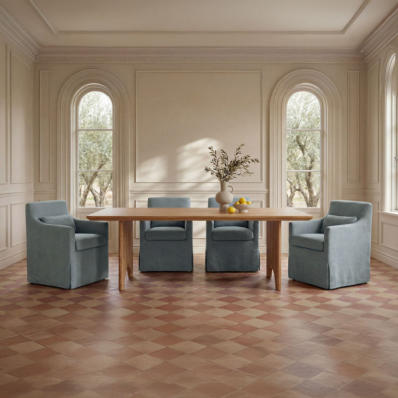 Natural wood dining table with four upholstered chairs in a light room setting