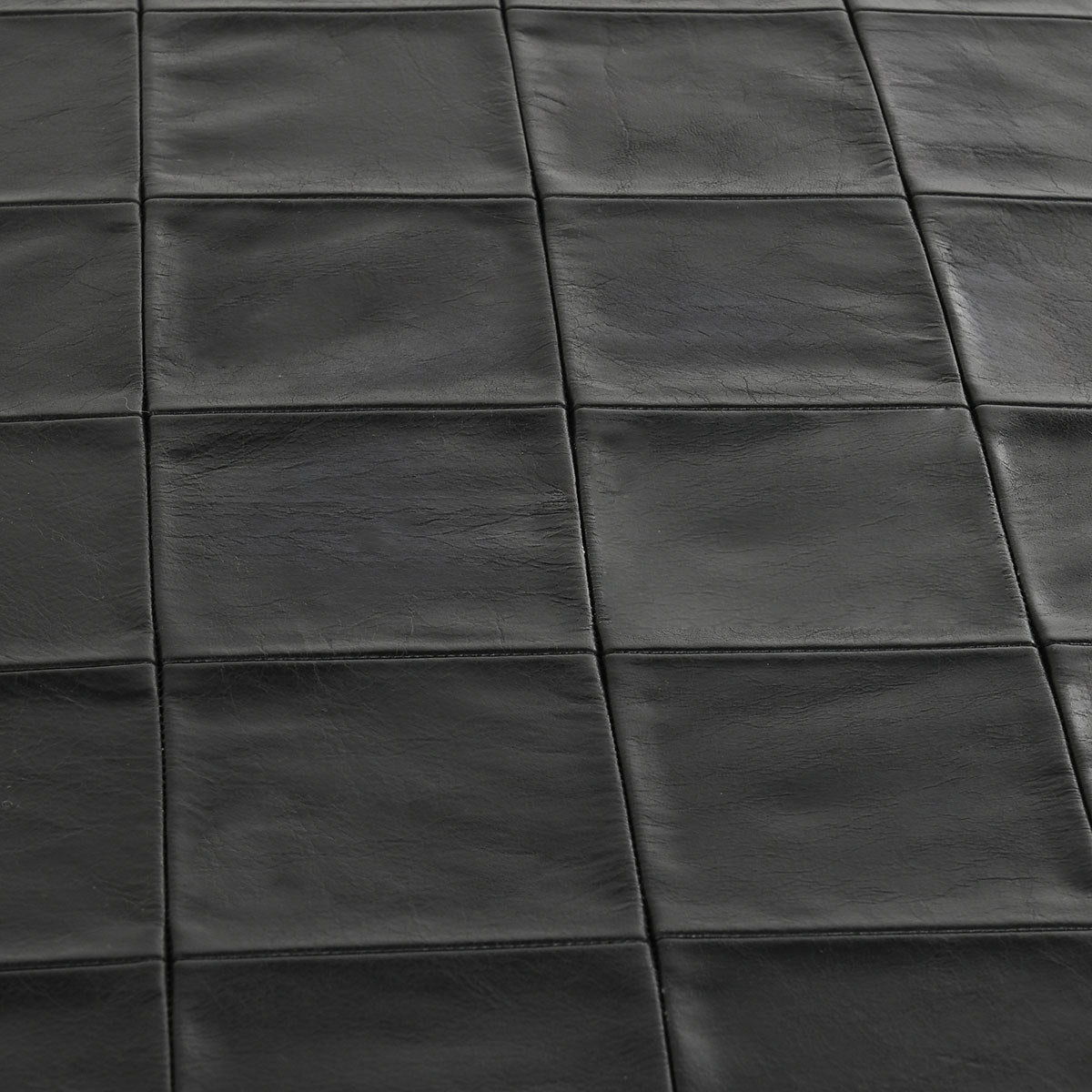 Close-up of dark leather bench seat with square stitched panels