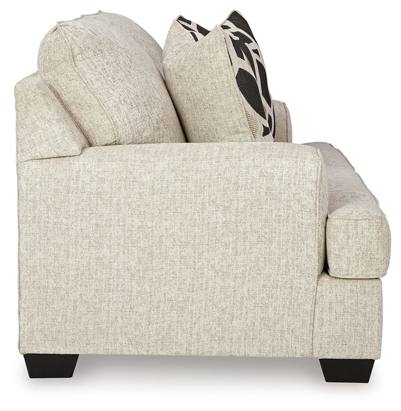 Beige loveseat with rounded armrest, wide seat, and patterned black-and-cream pillow