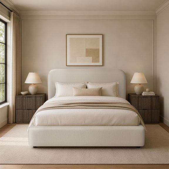 Beige upholstered bed with rounded headboard and layered white bedding