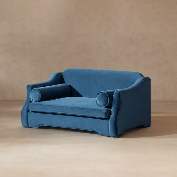 Blue dog sofa bed in angled view with cushioned sides, two bolster pillows, and base