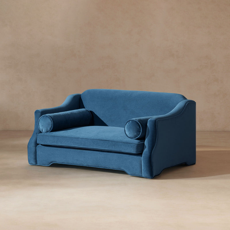 Blue dog sofa bed in angled view with cushioned sides, two bolster pillows, and base