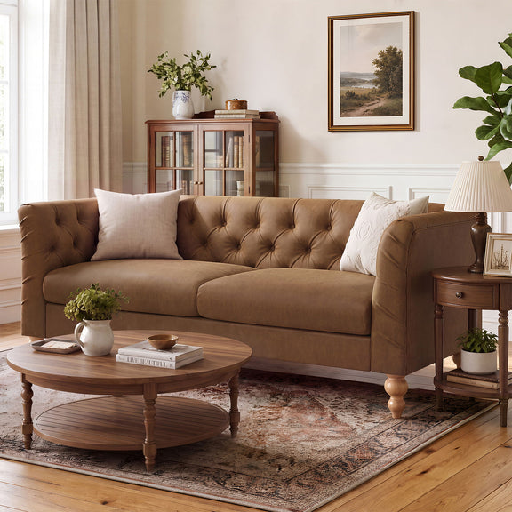 Tan chesterfield-style sofa with tufted back, flared arms, and exposed wooden legs