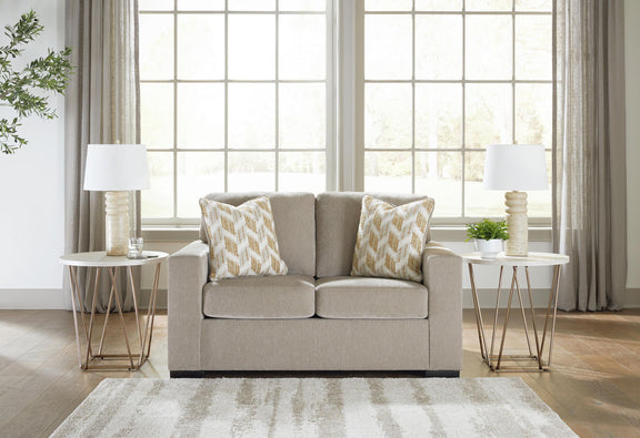 Beige loveseat with two patterned throw pillows and matching two-cushion seat