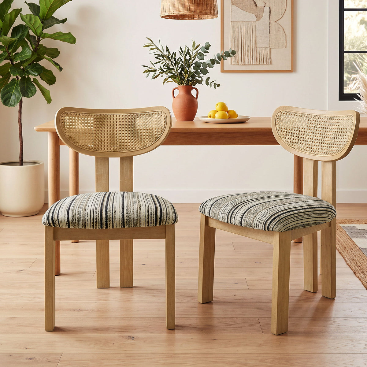 Pair of dining chairs with striped seats, light wood frames, and woven rattan backs