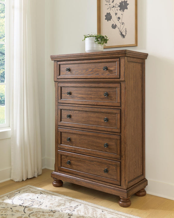 Zackaryn warm brown wood five drawer chest with arched trim and round metal knobs, bun feet.