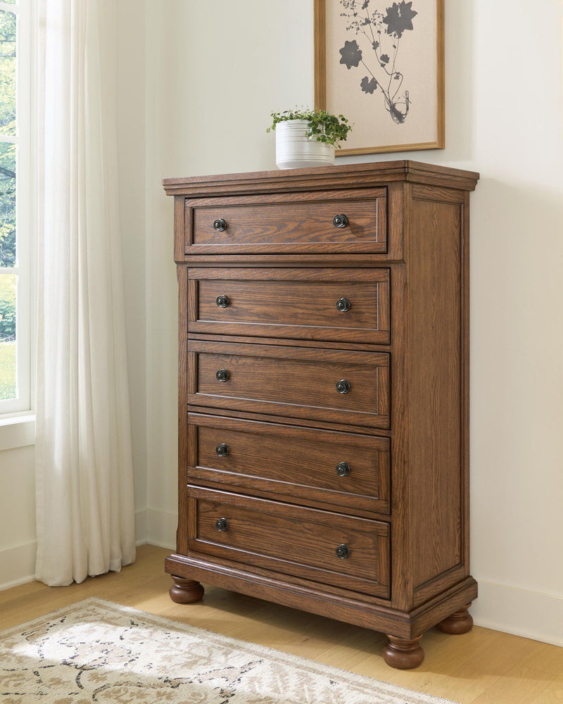 Zackaryn warm brown wood five drawer chest with arched trim and round metal knobs, bun feet.