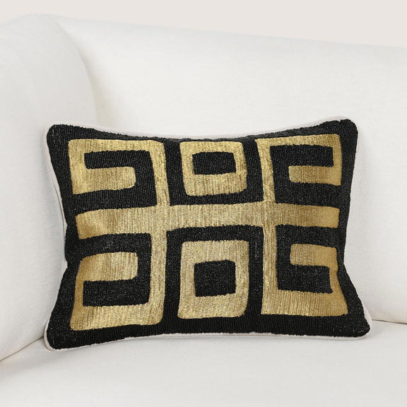 Black rectangular throw pillow with gold geometric Greek-key pattern, angled
