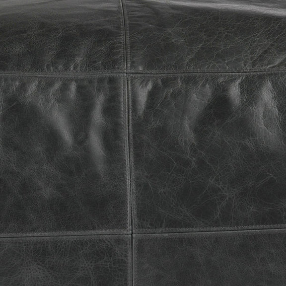 Close-up of onyx leather pouf seams and textured leather grain.