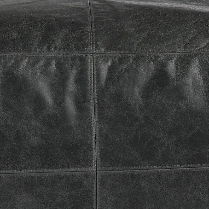 Close-up of onyx leather pouf seams and textured leather grain.