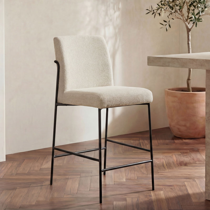 Ivory/beige fabric counter stool with curved back, black metal frame and lower bars.