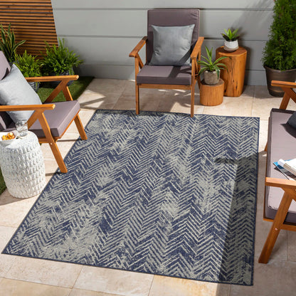 Blue indoor/outdoor area rug with white zigzag chevron pattern and flat weave.