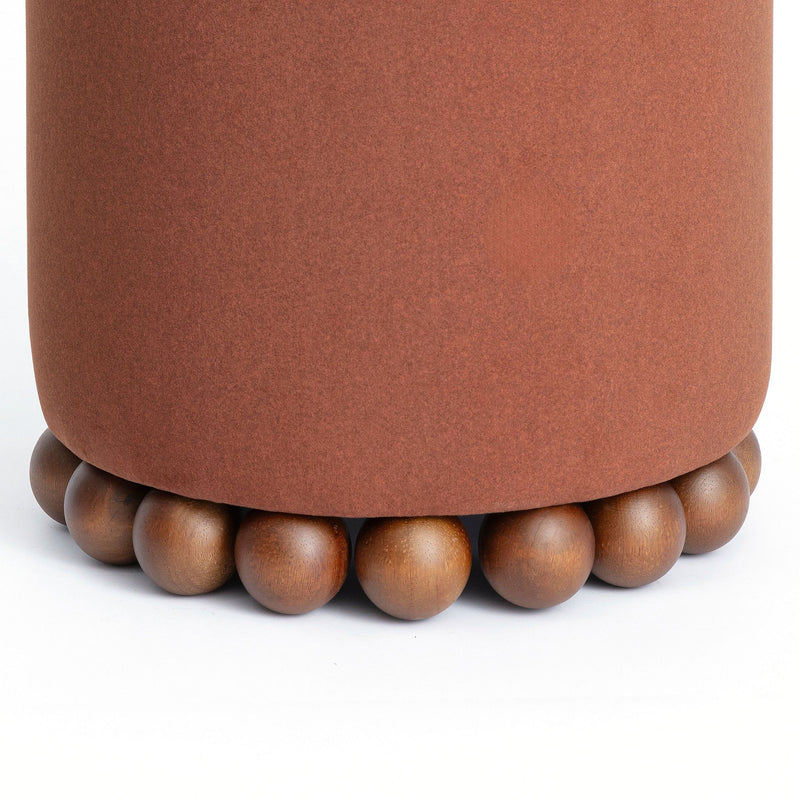 Close-up of rust-brown ottoman with beaded wooden base