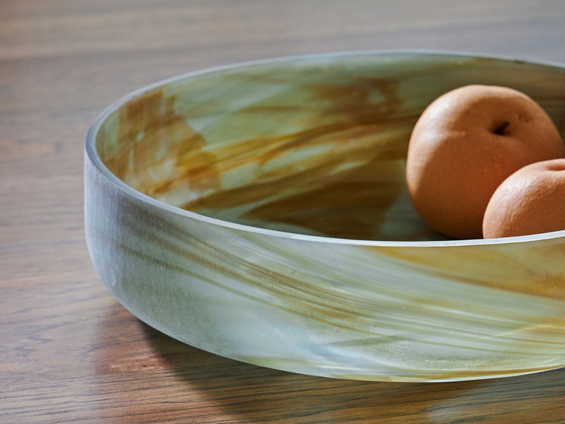 Sage green glass bowl with two orange decorative balls inside